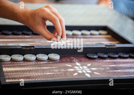 Lanci i dadi a mano in primo piano nella tradizionale partita di backgammon Foto Stock