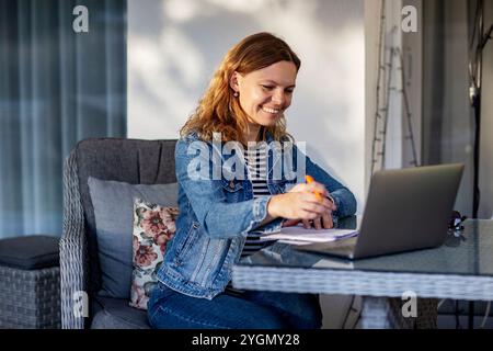 donna che utilizza un computer portatile seduto al tavolo in terrazza Foto Stock