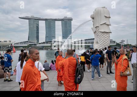 20.10.2024, Singapore, Repubblica di Singapore, Asia - gruppo di monaci buddisti nei loro tradizionali abiti arancioni visita con altri turisti al Merlion Park. Foto Stock