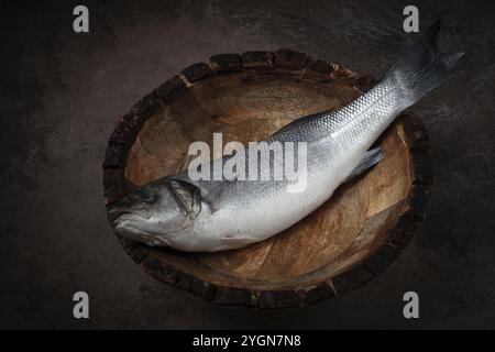 Pesce di spigola fresco e crudo, in un piatto di legno, vista dall'alto, non c'è gente Foto Stock