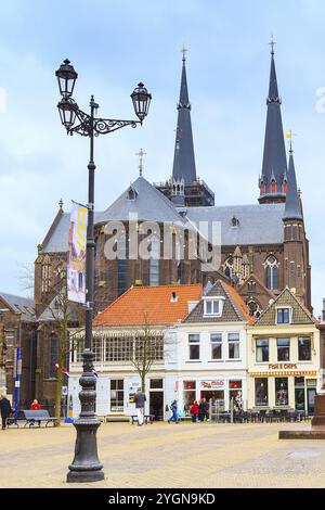 Delft, Paesi Bassi, 8 aprile 2016: Vista colorata sulla strada con tradizionali case olandesi, cattedrale, biciclette, persone nel centro della popolare Olanda Foto Stock