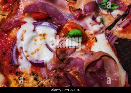 Delizioso prosciutto per pizza condito con ingredienti freschi e formaggio fuso servito su un rustico tavolo di legno Foto Stock