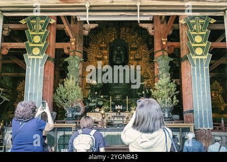 I turisti fotografano la statua in bronzo del grande Buddha al tempio Todaiji di Nara. La statua è alta 15 metri e pesa 452 tonnellate Foto Stock