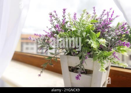 Pianta artificiale fiore viola in vaso di fiori su davanzale per interni, design degli interni Foto Stock