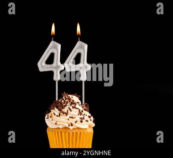 Numero 44 candele sagomate - cupcake di compleanno su sfondo nero. Foto Stock