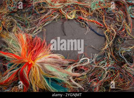 Fili colorati aggrovigliati su sfondo grigio scuro Foto Stock