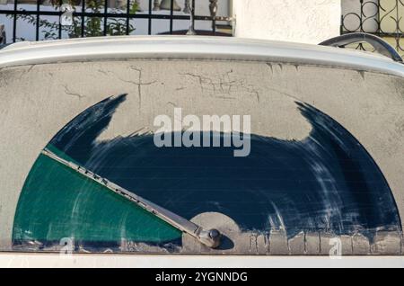 protezione lunotto telaio cristallo sporco, tergicristallo. parte della macchina dal retro. forma astratta di batman. lavate la vostra auto concept. Foto Stock