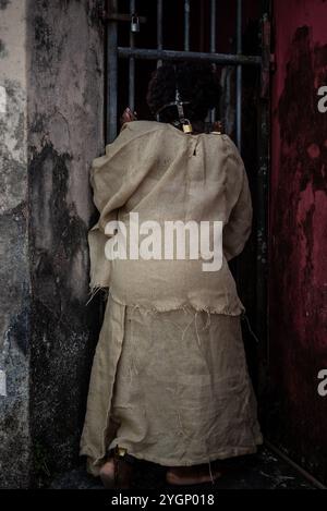 Ritratto di una donna nera vestita da schiava, incatenata con una maschera di ferro sulla bocca, rivolta lontano dalla recinzione di ferro. Schiavitù in Brasile. Ripresentato Foto Stock