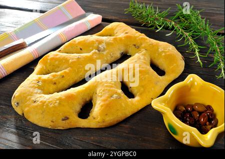 Focaccia a foglia su un tavolo in legno nero, con olive e rosmarino Foto Stock