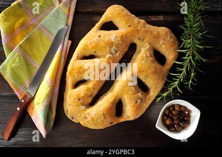 Focaccia a foglia su un tavolo in legno nero, con olive e rosmarino Foto Stock
