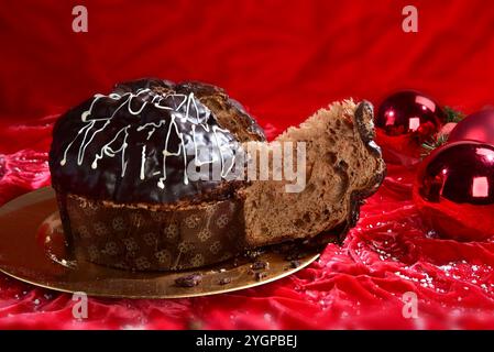 Panettone al cioccolato fatto in casa su un piatto dorato e sfondo rosso Foto Stock