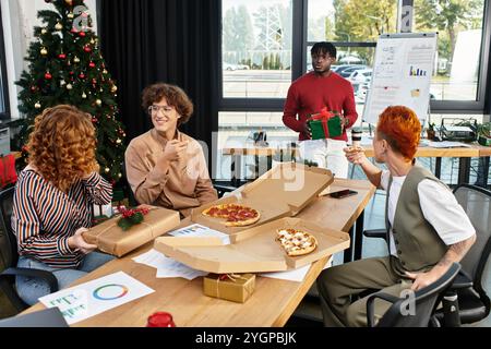 Un gruppo di allegri colleghi si diverte a festeggiare il Natale nel loro ufficio con regali. Foto Stock