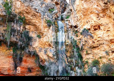 Una splendida cascata scorre giù da aspre scogliere, circondate dal verde e dalle affascinanti formazioni rocciose. Foto Stock