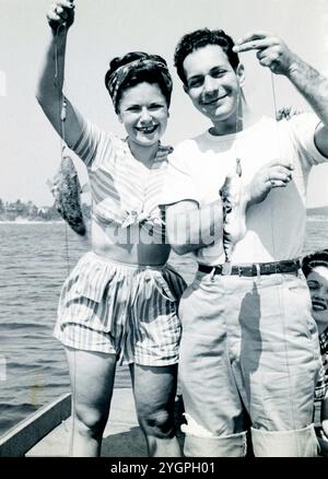 Gita di pesca del Labor Day del 1946; una giovane coppia su una barca che regge 2 piccoli pesci. Foto Stock