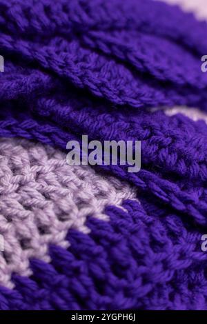 il primo piano di una coperta a zigzag viola lilla piegata con accenti viola reale, all'uncinetto o a maglia, ricorda la casa della nonna, accogliente e calda Foto Stock
