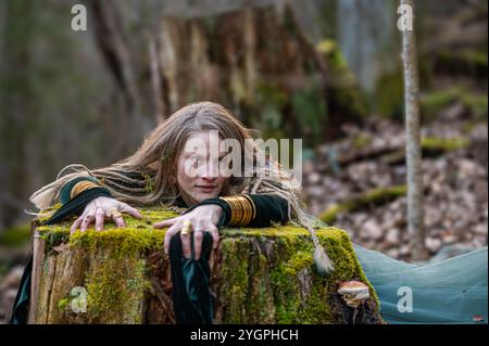 Una donna si appoggia su un tronco di albero coperto di muschio in una foresta. Profondità bassa del campo Foto Stock