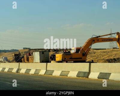 Giza, Egitto, ottobre 25 2024: I camion da costruzione pesanti per lo sviluppo vicino alla strada sulla tangenziale di Giza, progetti immobiliari egiziani e. Foto Stock