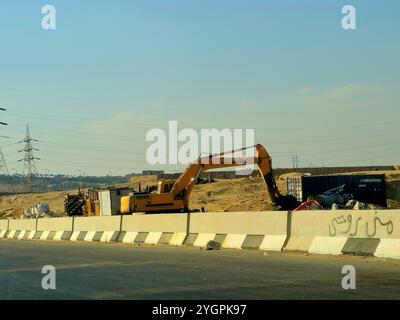 Giza, Egitto, ottobre 25 2024: I camion da costruzione pesanti per lo sviluppo vicino alla strada sulla tangenziale di Giza, progetti immobiliari egiziani e. Foto Stock