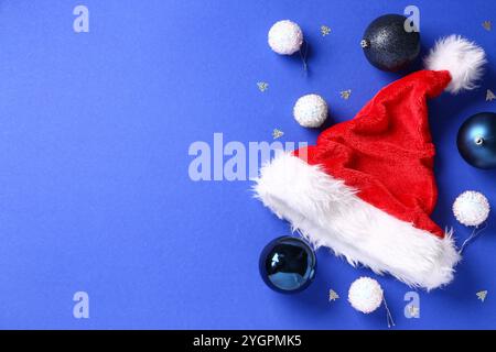 Cappello di Babbo Natale con palle di Natale e coriandoli su sfondo blu Foto Stock