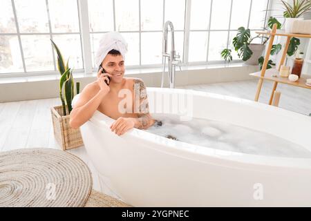 Bell'uomo che parla al telefono cellulare nella vasca da bagno di casa Foto Stock