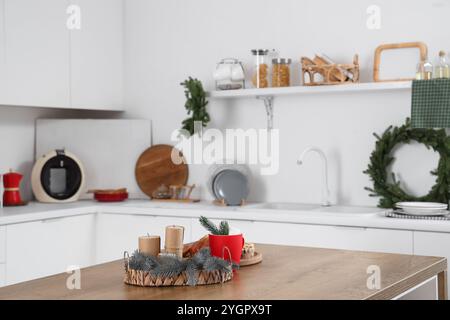 Candele, rami di abete e una tazza di cioccolata calda sul tavolo nella cucina delle feste. Festa di Natale Foto Stock