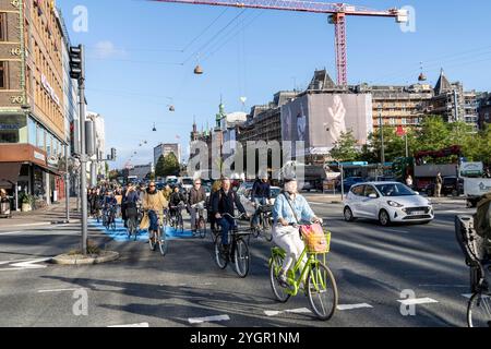 Uomini e donne che viaggiano in bicicletta attraverso il centro di Copenaghen in una pista ciclabile dedicata accanto ai veicoli a motore Foto Stock