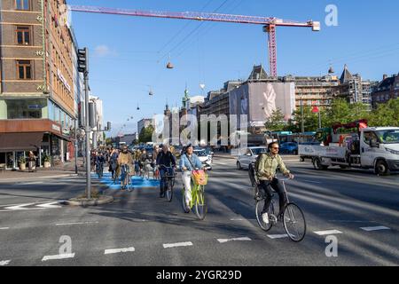 Uomini e donne che viaggiano in bicicletta attraverso il centro di Copenaghen in una pista ciclabile dedicata accanto ai veicoli a motore Foto Stock