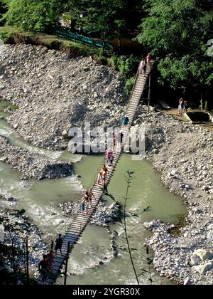 Krasnodar Krai, Sochi District, Russia giugno 2023 Un gruppo di turisti attraversa un ponte su un fiume di montagna. Foto Stock