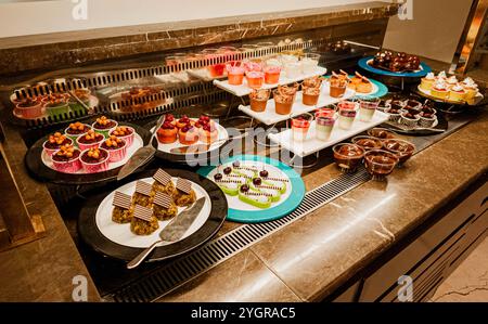 Un elegante buffet di dessert con una varietà di dolci colorati, dolci e prelibatezze di cioccolato per un'esperienza culinaria appagante. Foto Stock