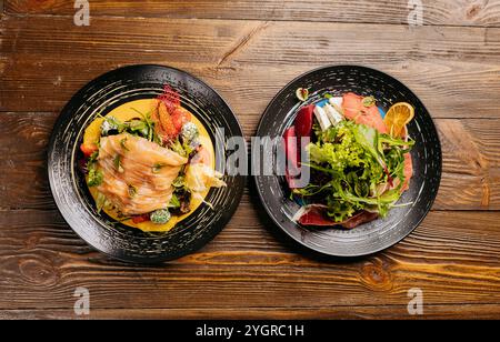 Piatti per insalate gourmet con salmone affumicato, verdure fresche e decorazioni vivaci su un rustico tavolo in legno Foto Stock