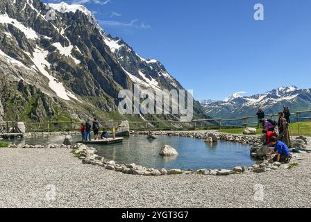 I bambini si divertono ad attraversare un laghetto su una zattera alla stazione della funivia Pavillon (2173 m) della Skyway Monte bianco in estate, Courmayeur, Aosta, Italia Foto Stock