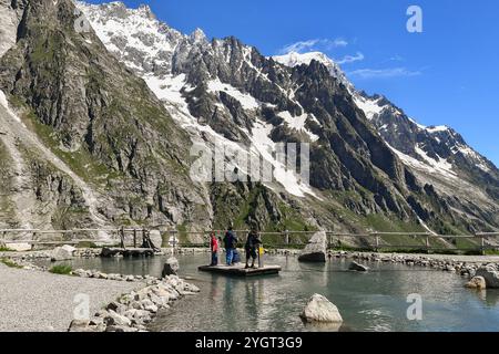 I bambini si divertono ad attraversare un laghetto su una zattera alla stazione della funivia Pavillon (2173 m) della Skyway Monte bianco in estate, Courmayeur, Aosta, Italia Foto Stock