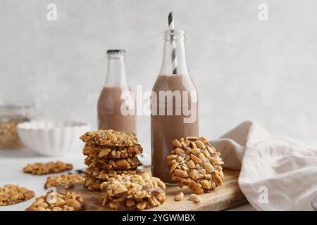 Un mucchio di tradizionali biscotti alle arachidi portoghesi conosciuti come Bolachas de Amendoim sul bordo di legno con due bottiglie di latte di cacao, tovagliolo e un piatto di Foto Stock