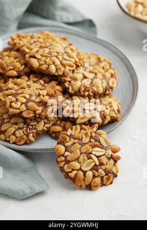 Un mucchio di tradizionali biscotti alle arachidi portoghesi conosciuti come Bolachas de Amendoim sul piatto grigio con un tovagliolo su sfondo grigio Foto Stock