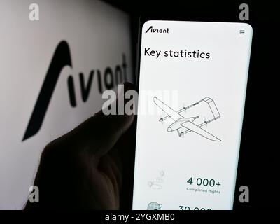In questa immagine, una persona ha in mano un cellulare con la pagina web della società norvegese di servizi di droni Aviant, COME davanti al logo aziendale. Foto Stock