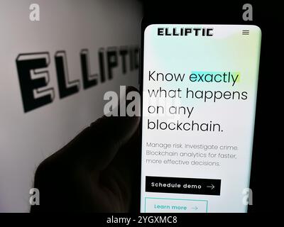 In questa illustrazione fotografica, una persona ha in mano un cellulare con la pagina web della società blockchain britannica Elliptic Enterprises Limited con il logo. Foto Stock