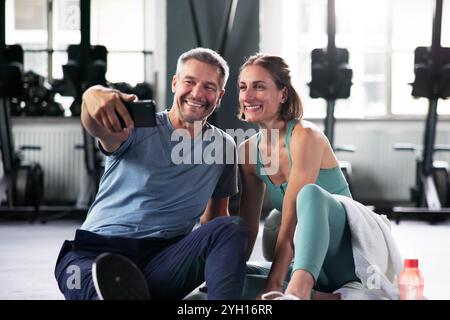 Coppia sorridente che parla in palestra. Riposati dopo l'allenamento insieme Foto Stock