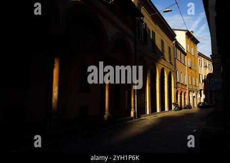 Stretta strada acciottolata di Bologna, Italia illuminata dalla calda luce del mattino Foto Stock