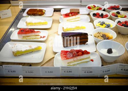 Traversetolo, Parma, Itally - 6 novembre 2024 invitanti fette di torte e dessert con condimenti di frutta fresca sono esposti in vetrina di una pasticceria, Foto Stock