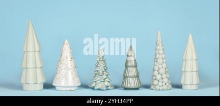 Banner con alberi di Natale in ceramica verde chiaro di diversa forma su sfondo blu Foto Stock