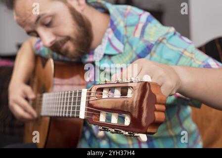 Uomo hipster barbato che regola la chitarra acustica. Messa a fuoco selettiva in primo piano Foto Stock