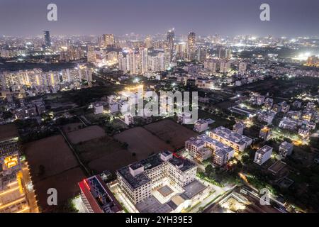 Ripresa aerea del paesaggio urbano di Delhi con piccoli centri commerciali, centri commerciali, uffici, case di grattacieli in lontananza con strade ben illuminate Foto Stock