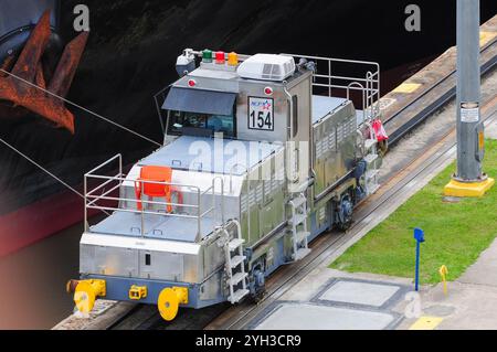 Città di Panama, Provincia di Panama, Panama. 4 giugno 2011: Una locomotiva del Canale di Panama guida una grande nave attraverso le chiuse. Foto Stock