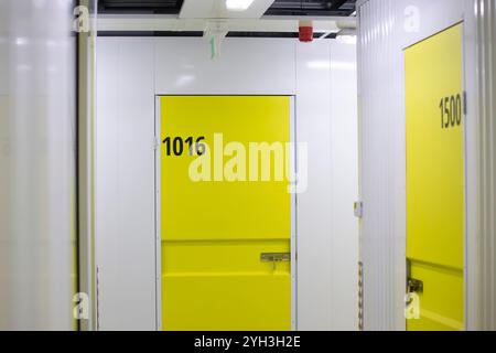 Armadietti di stoccaggio gialli numerati in una struttura ben illuminata, che offrono soluzioni di stoccaggio sicure e organizzate. Foto Stock