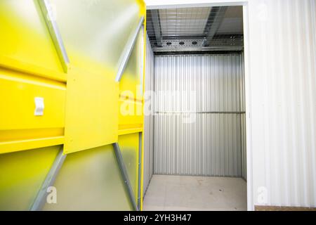 Aprire lo sportello giallo che rivela un'unità di stoccaggio vuota con pareti metalliche all'interno di una struttura. Foto Stock