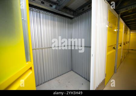 Aprire lo sportello giallo che rivela un'unità di stoccaggio vuota con pareti metalliche all'interno di una struttura. Foto Stock