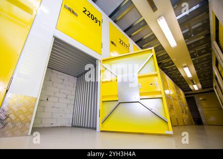 Aprire lo sportello giallo che rivela un'unità di stoccaggio vuota con pareti metalliche all'interno di una struttura. Foto Stock