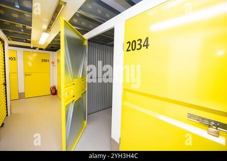Aprire lo sportello giallo che rivela un'unità di stoccaggio vuota con pareti metalliche all'interno di una struttura. Foto Stock