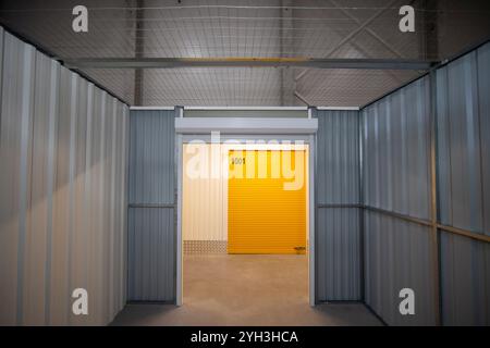 Interno di un vano portaoggetti vuoto con pareti metalliche con vista su una porta arrotolabile gialla. Foto Stock