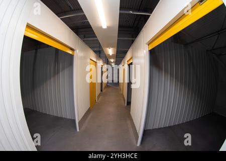 Interno di un vano portaoggetti vuoto con pareti metalliche con vista su una porta arrotolabile gialla. Foto Stock